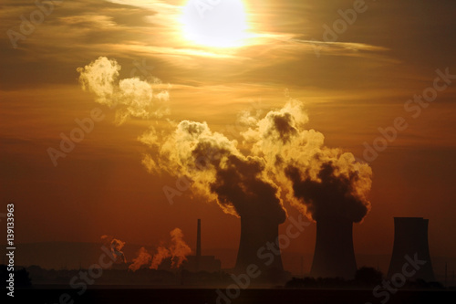 sun set over smoking nuclear power plant