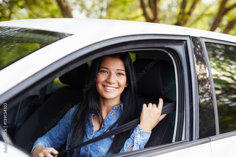 Young woman fasten seat belt in her car