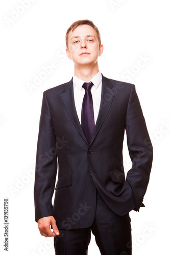 Young handsome businessman in black suit is standing straight, portrait isolated on white background