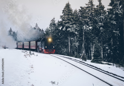 historic steam train driving through snow covered forrest