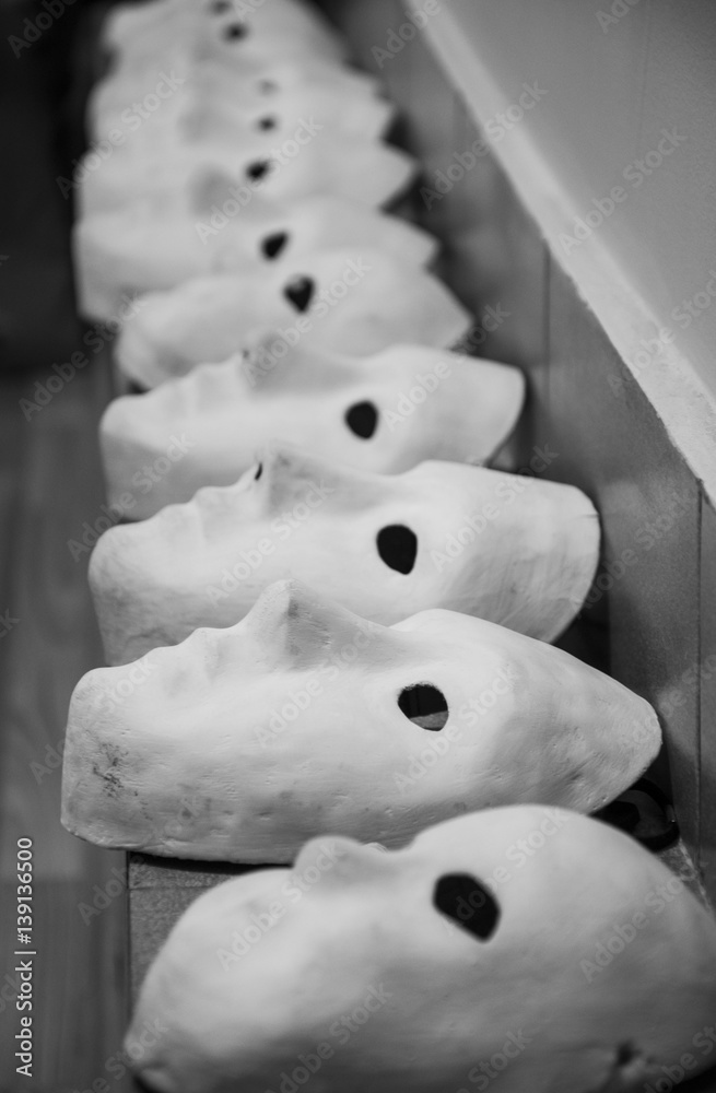 Black and white photo of white gypsum masks under the theater wall