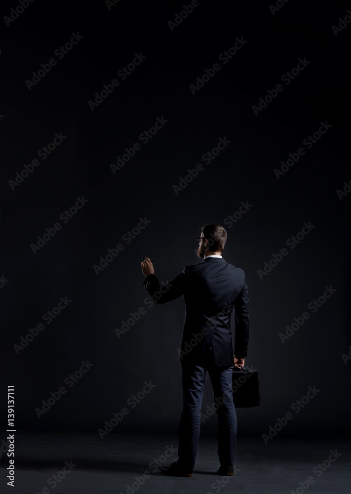 Businessman writing something over black background with copyspace. Business and office concept. Businessman writing something over black background with copyspace. Business and office concept.