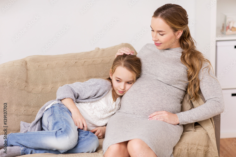happy pregnant woman and girl on sofa at home happy pregnant woman and girl on sofa at home
