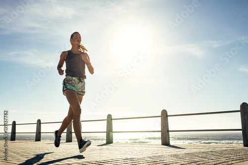 Fototapet Fitness young woman jogging along the beach