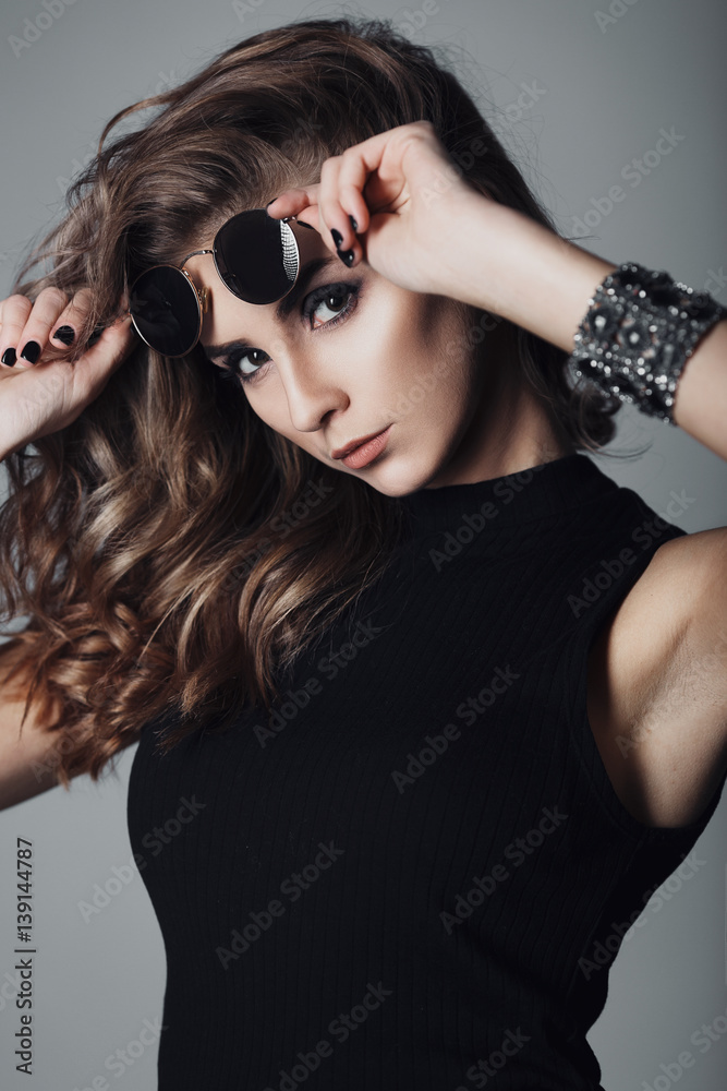Fashion studio portrait of young sexy woman with perfect skin. Girl in sunglasses.