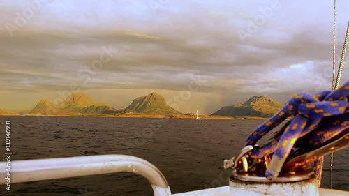 Amazing sunset in Norway with rainbow between low clouds. View from yacht board photo