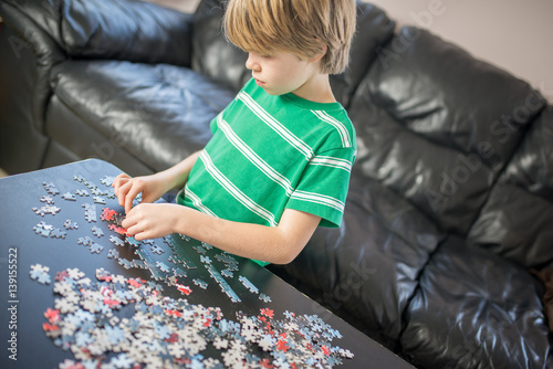 Cute boy doing a puzzle at table
