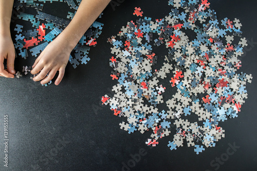 Photography Hands of a child doing a puzzle at table