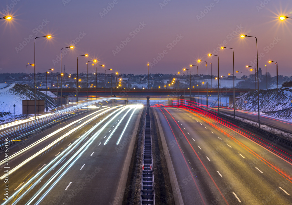 Car light beams on highway at sunset