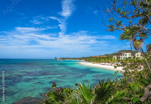 Landscape of a tropical  blue ocean water and sandy beach in Roatan island. Blue cloudy sky in the background.