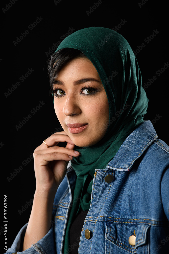 Portrait of a beautiful Muslim woman dressed in hijab on a black background in photo studio. Portrait of a beautiful Muslim woman dressed in hijab on a black background in photo studio.