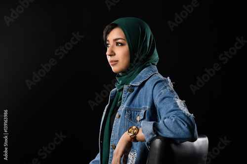 Portrait of a beautiful Muslim woman dressed in hijab on a black background in photo studio. photo