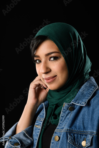 Portrait of a beautiful Muslim woman dressed in hijab on a black background in photo studio. photo