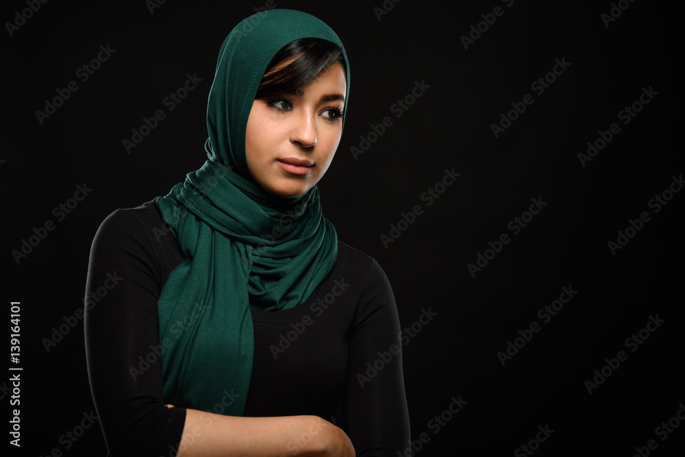Portrait of a beautiful Muslim woman dressed in hijab on a black background in photo studio. Portrait of a beautiful Muslim woman dressed in hijab on a black background in photo studio.