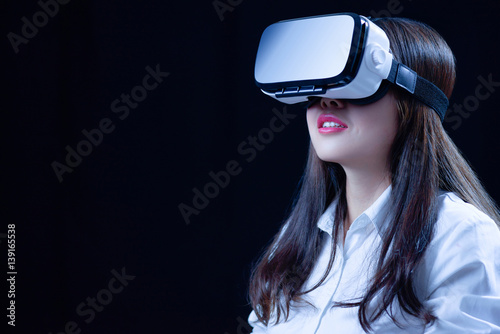 Asian Chinese young woman using vitual reality smart glasses in vitual space.low key photo