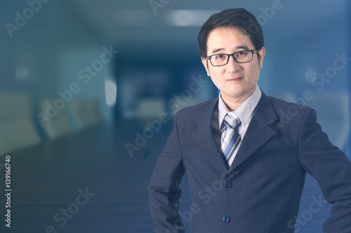 Double exposure of confident Asian businessman shaking hand in meeting room.