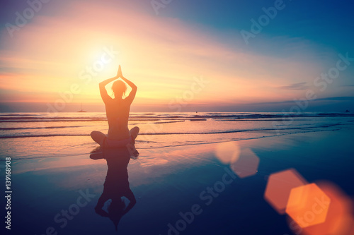 Woman doing meditation near the ocean beach.