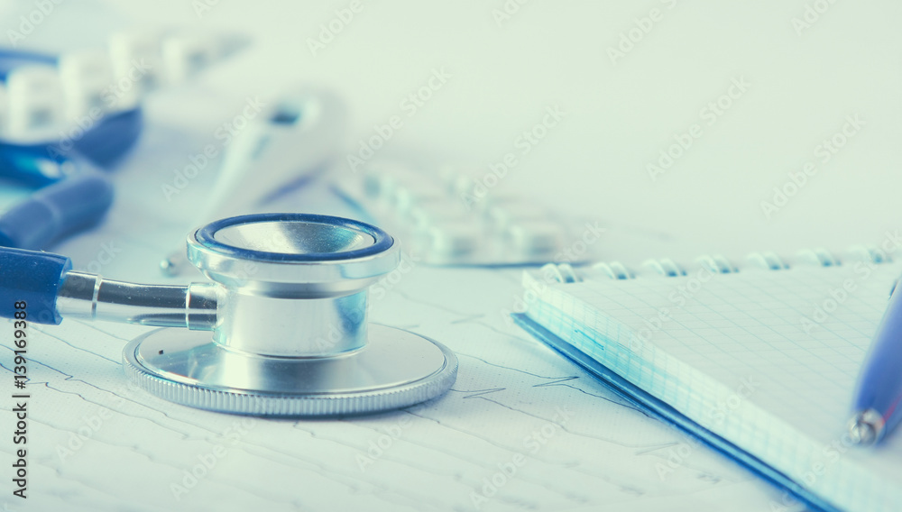 Medical stethoscope lying on cardiogram with pile Medical stethoscope lying on cardiogram with pile