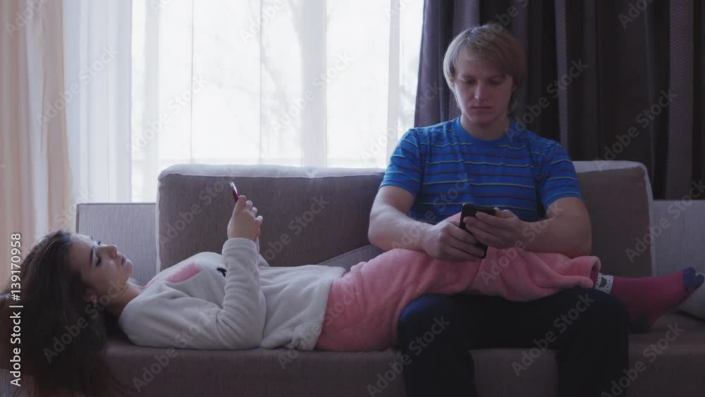 family, technology, relationship difficulties and people concept - couple with smartphones texting at home family, technology, relationship difficulties and people concept - couple with smartphones texting at home