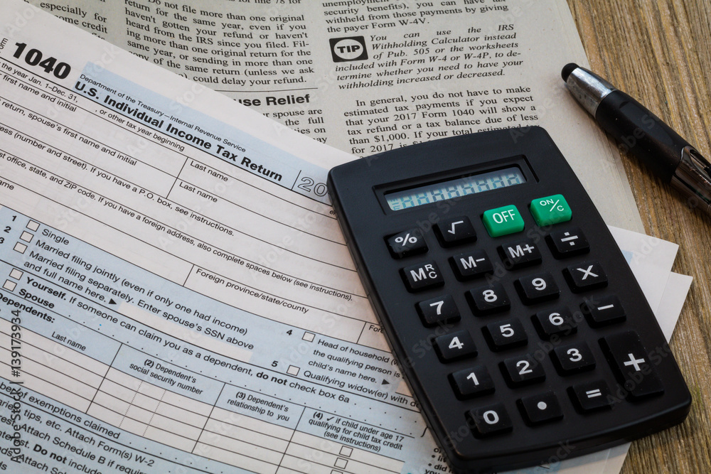 Tax preparation form 1040 detail and instruction booklet with calculator and pen on wood board Tax preparation form 1040 detail and instruction booklet with calculator and pen on wood board