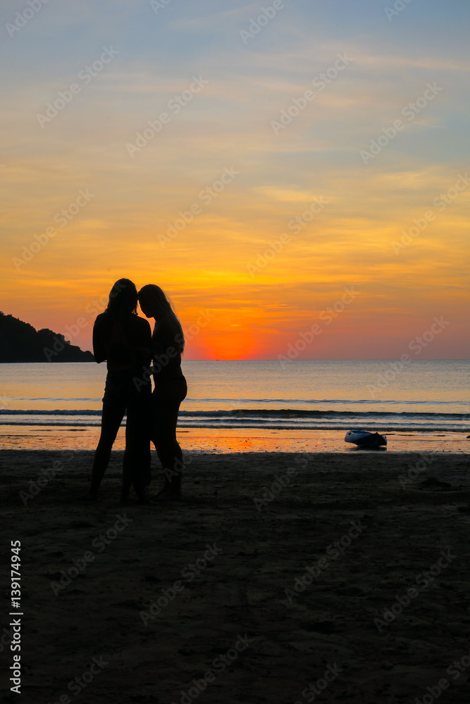 Fototapeta premium Two Models Checking Their Phone on an Island Beach