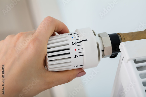 Woman's Hand Adjusting Thermostat Valve