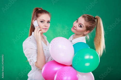Two girls with mobile phone and balloons