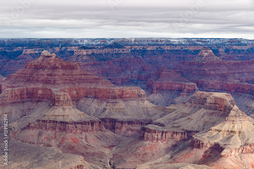 Panoramic view of the Grand Canyon in winter, portraying the colorful formations of the canyon's north side. The top edge of the canyon sports a thin stripe of snow from the just concluded storm. 