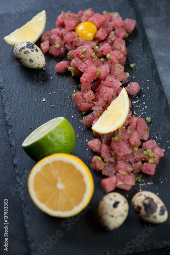 Tuna tartar served with quail egg yolk  lemon and lime  close-up