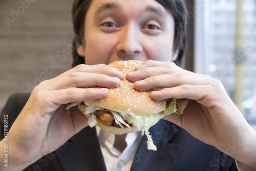Man in business suit eating hamburge
