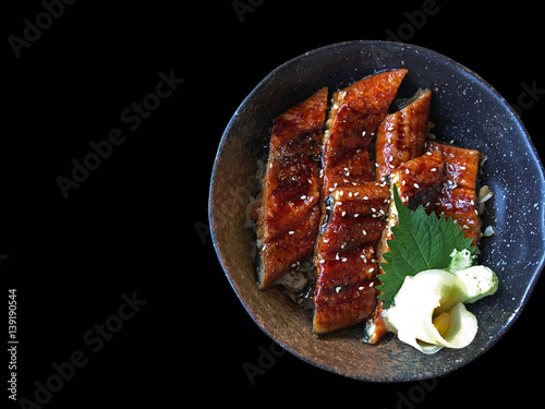 Unagi don (Unadon), steamed white rice topped with fillet of freshwater eel grilled, Japanese food on black background, top view. photo