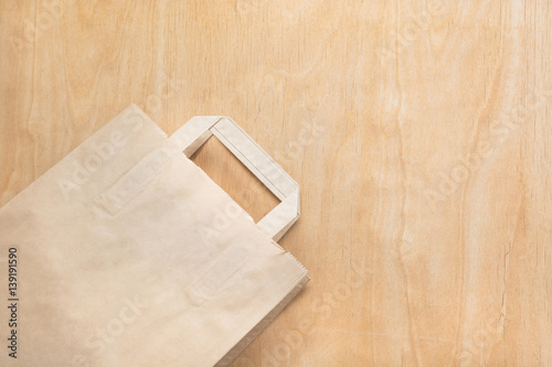 Clean brown kraft paper bag lying on a plywood table. Mock up.