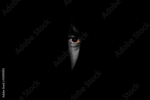фотографія red eye of man looking  through the hole in the dark