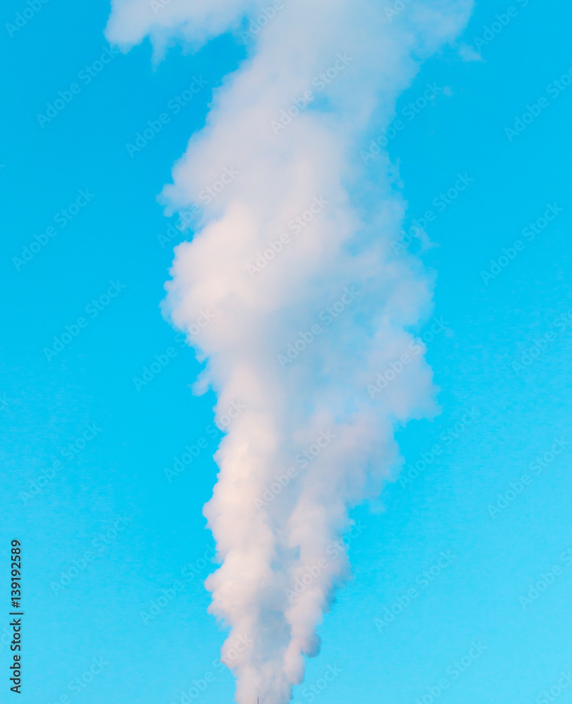 white industrial smoke from the chimney on a blue sky