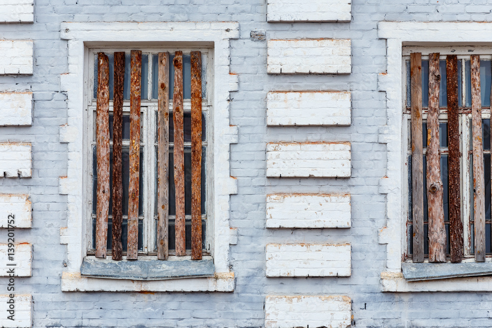 Part of the facade of the old brick building with boarded up windows.