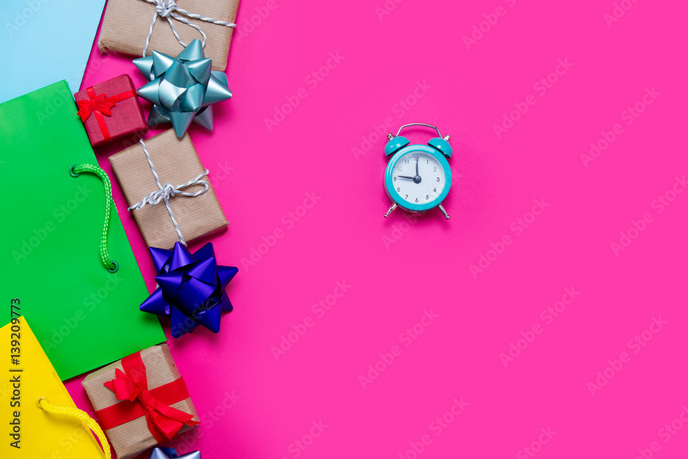 beautiful small gifts, bows, alarm clock and colorful cool shopping bags on the wonderful pink background beautiful small gifts, bows, alarm clock and colorful cool shopping bags on the wonderful pink background