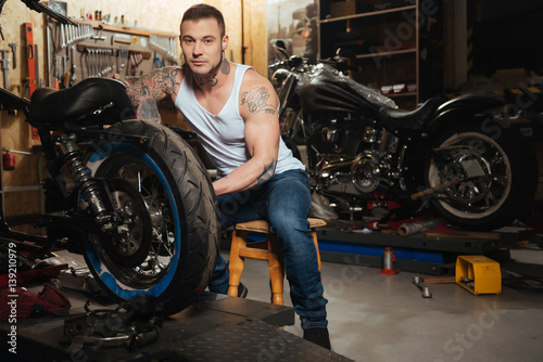 Handsome motorcyclist posing in the workshop