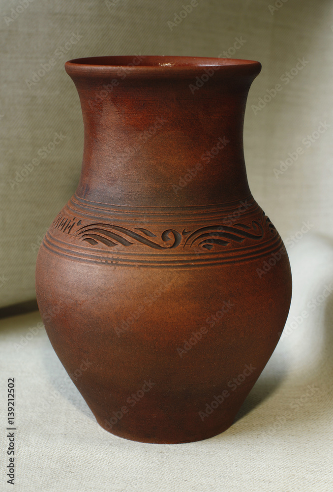 One clay pot on the background of linen cloth close up