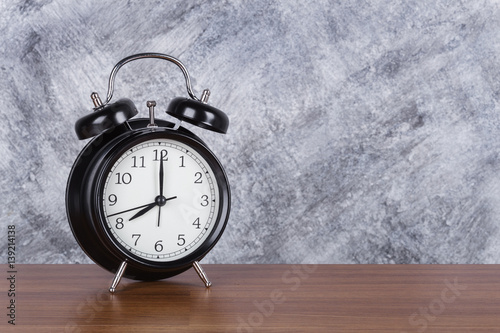 8 o'clock vintage clock on wood table and wall background photo