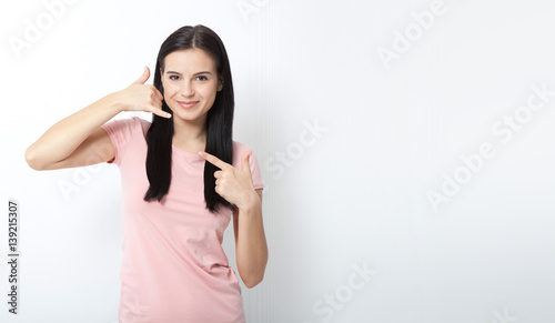 Call me. Woman showing sign and smiling on white.