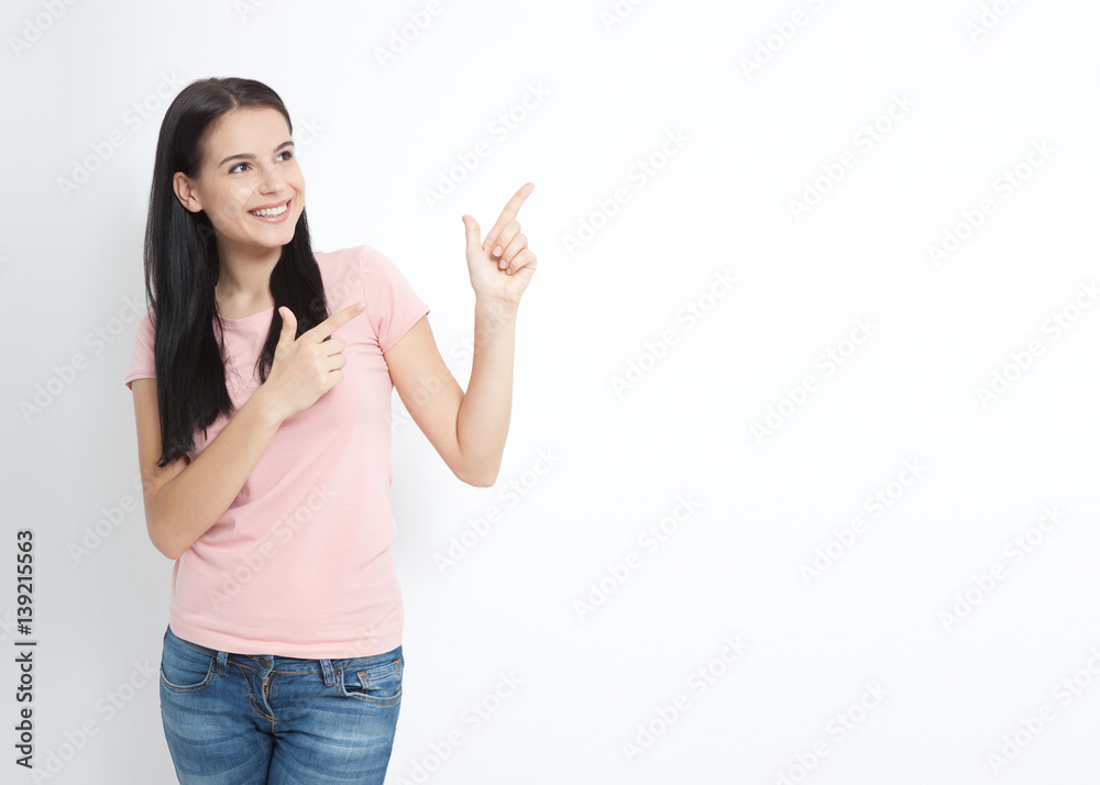 Look here. Attractive young woman pointing to space. Friendly smiling girl pointing at copyspace isolated on white background Look here. Attractive young woman pointing to space. Friendly smiling girl pointing at copyspace isolated on white background