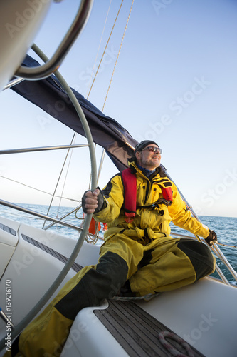 Smiling Mature Man Stirring Yacht In Sea