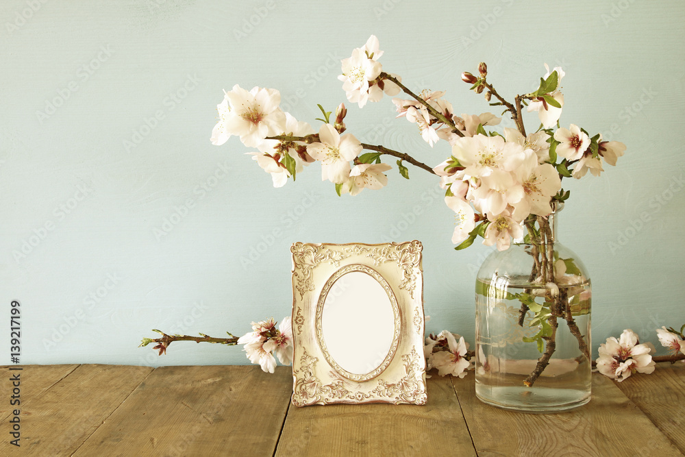 Obraz premium Vintage blank photo frame next to spring flowers