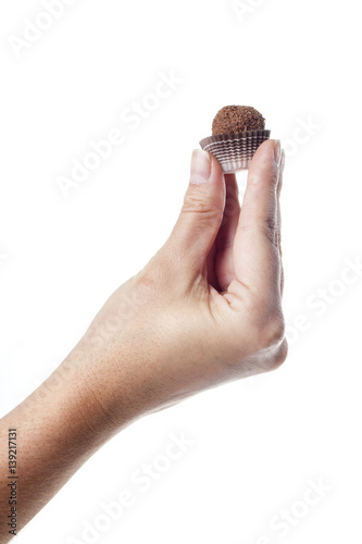 Hand holding a traditional candy from Brazil called brigadeiro over white background