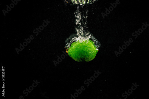 Sparkling green lime splashes water on black background © IVASHstudio