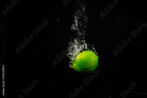 Sparkling green lime splashes water on black background © IVASHstudio
