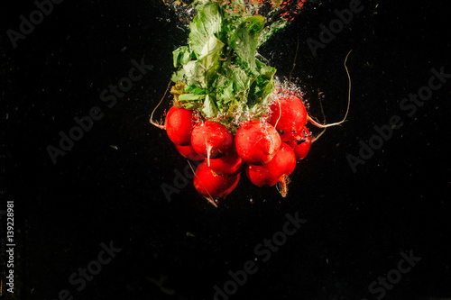 Bunch of red redish falls on black background