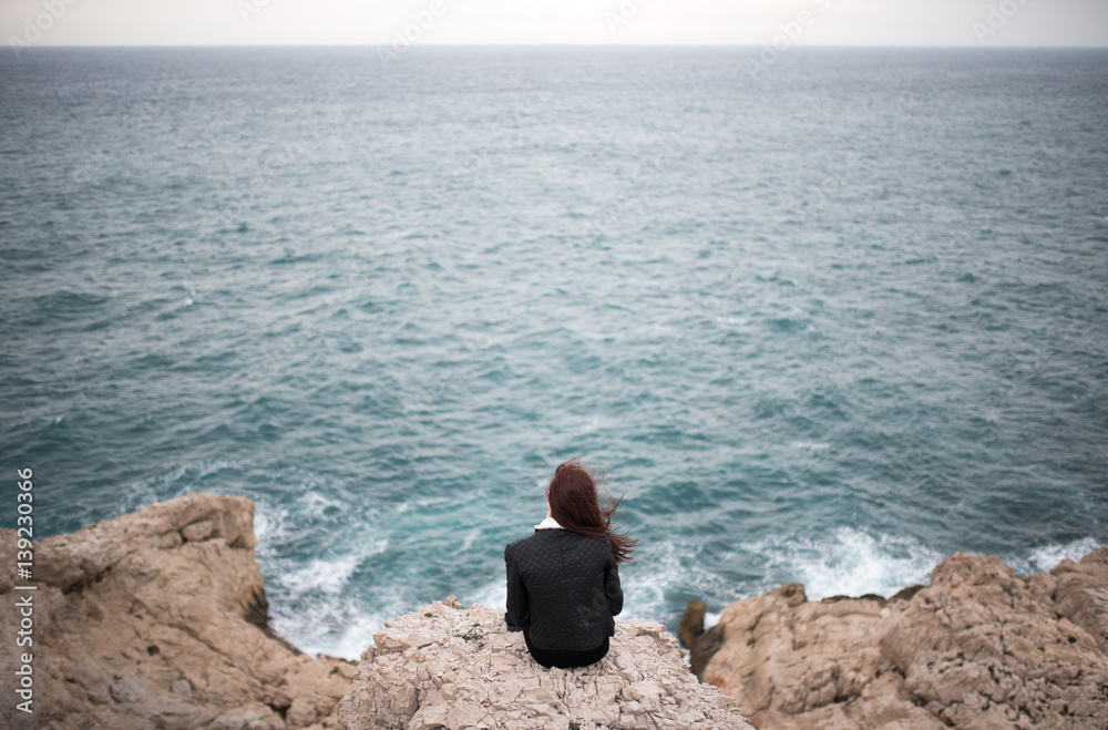 Jeune-fille seule de dos au bord de la mer Photos | Adobe Stock