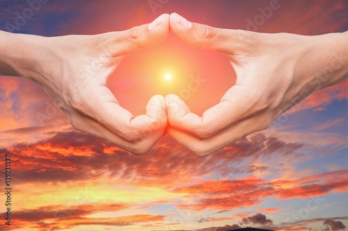 hand forming a heart shape with sunset light and copy space for add text
