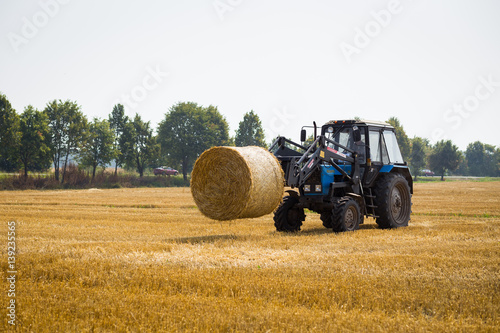 Vinnitsa Ukraine - July 26 2016.huge tractor collecting haystack in the field at nice blue sunny day Tractor collecting straw bales Agricultural machine collecting bales of hay harvest concept
